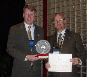 Galco’s Scott Feck (right) accepts the Golden Bullseye from NRA’s Mark Keefe IV.